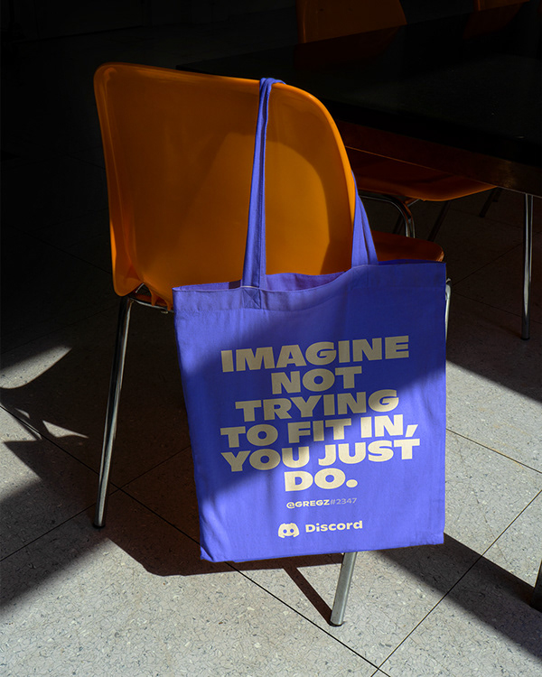 Branded purple tote with community-focused messaging on a modern chair