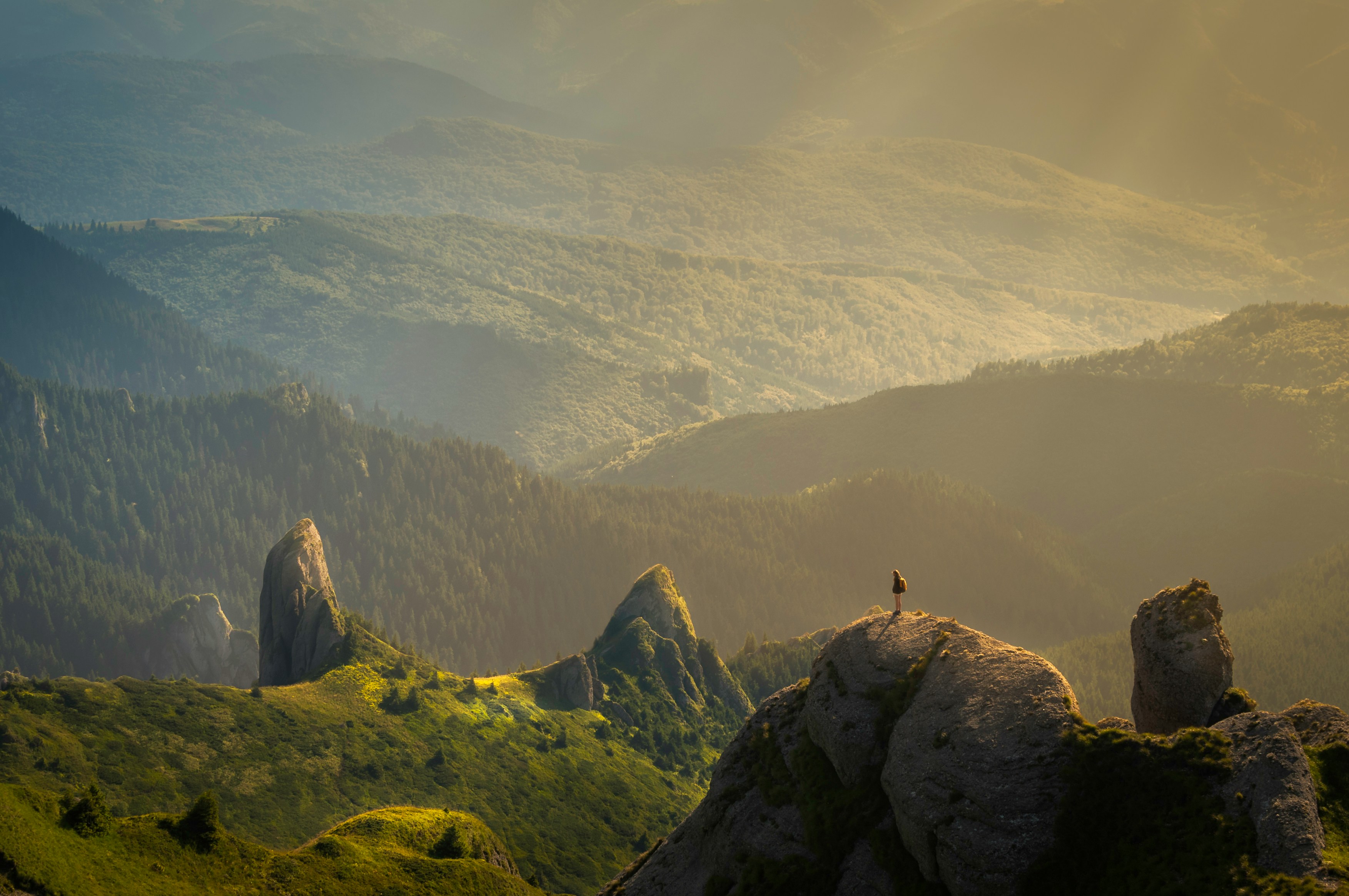 A person standing on some small mountain peaks overlooking valleys.