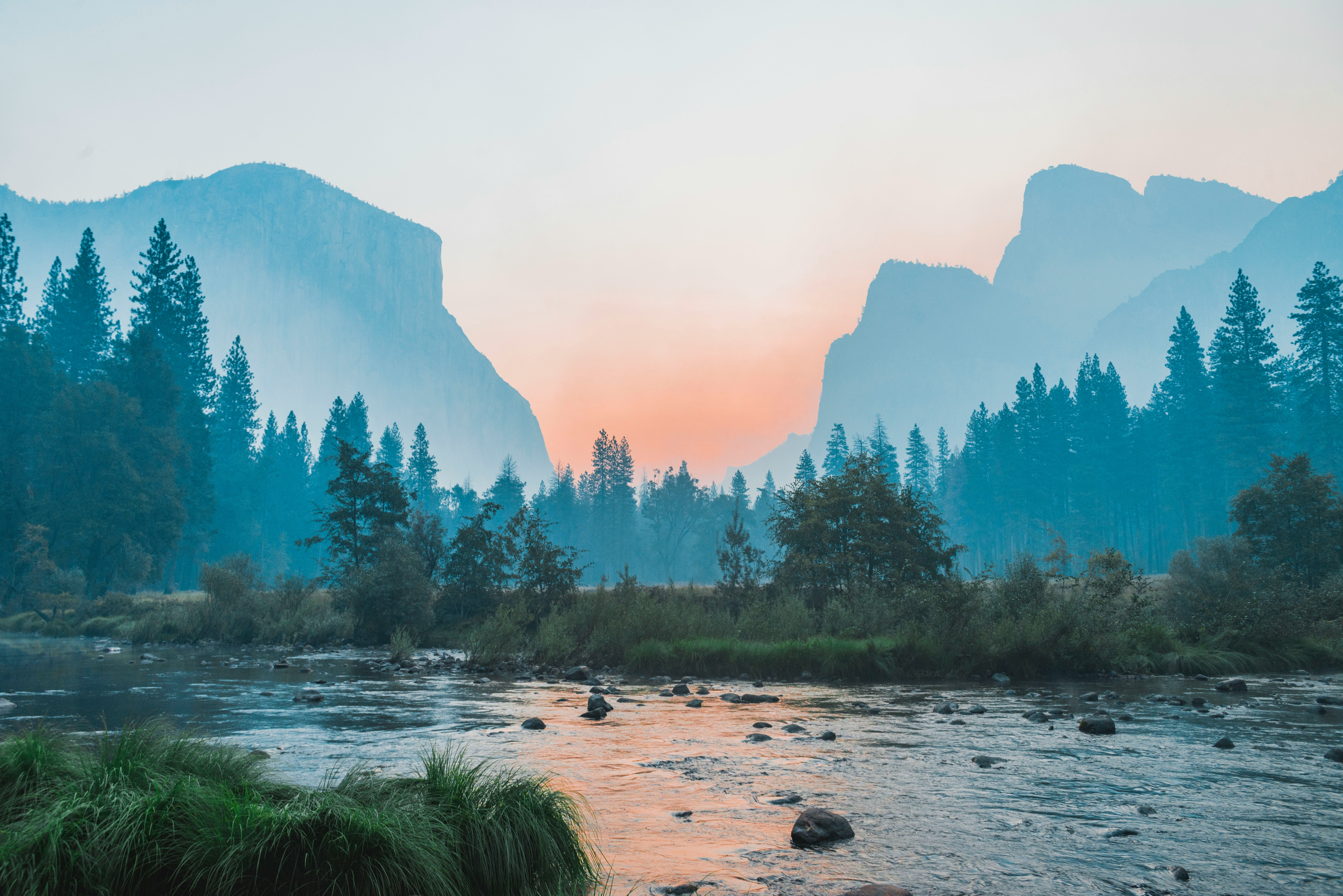 A river with 2 large light blue mountains in the distance.