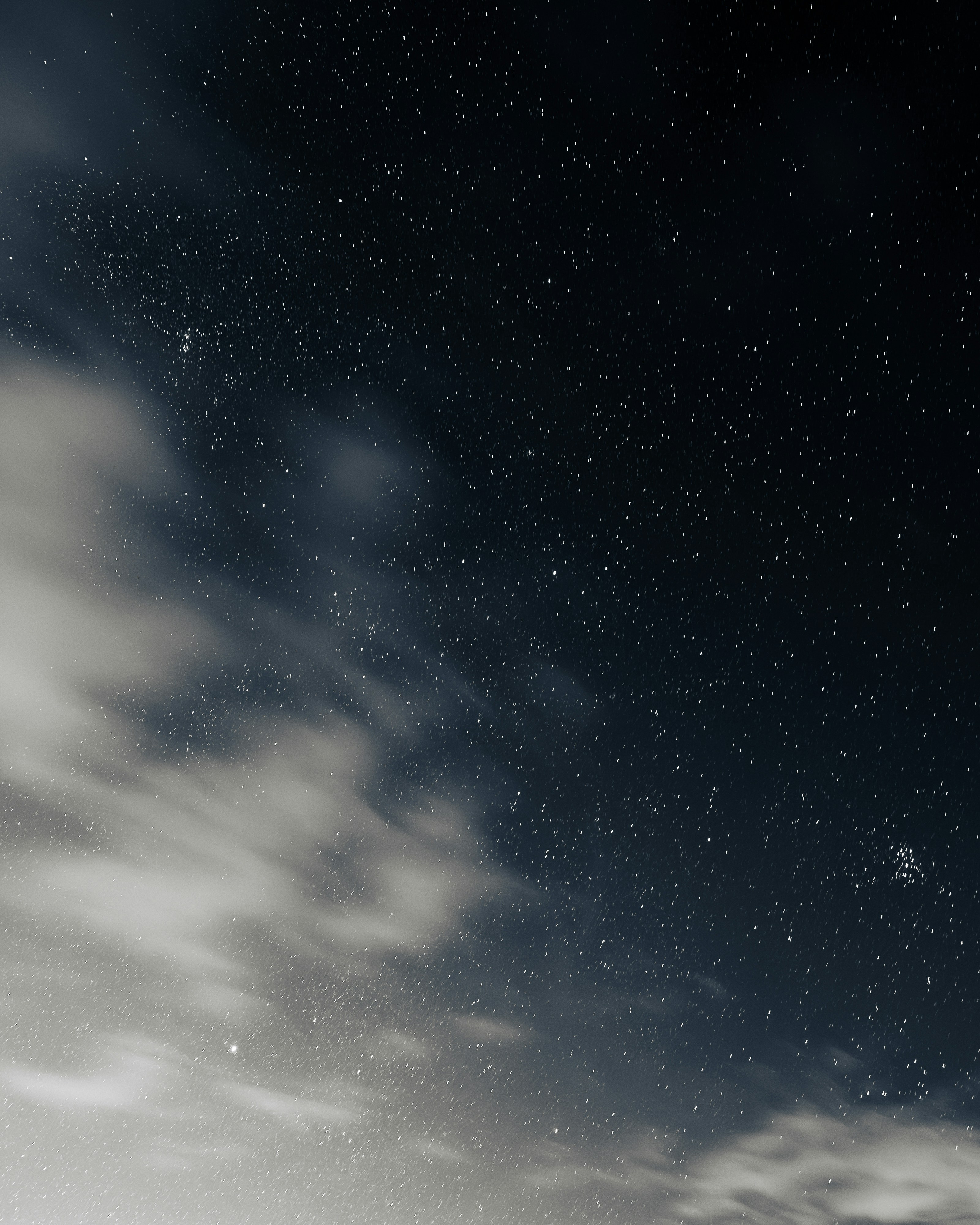 A starry sky in front of some blurred clouds.