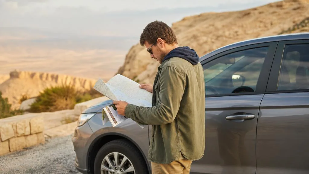 Traveler reviewing a Jordan itinerary beside a private vehicle