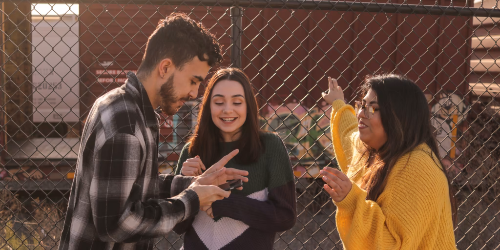 Trois ados qui discutent. L'un d'eux a un téléphone en main.