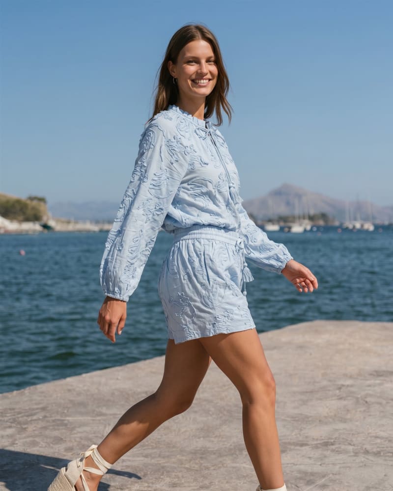 Blusa y shorts bordados en azul cielo junto al mar, moda ecommerce con modelo virtual