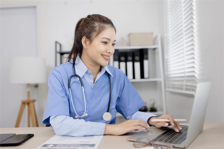 Healthcare professional working on medical documentation at a laptop