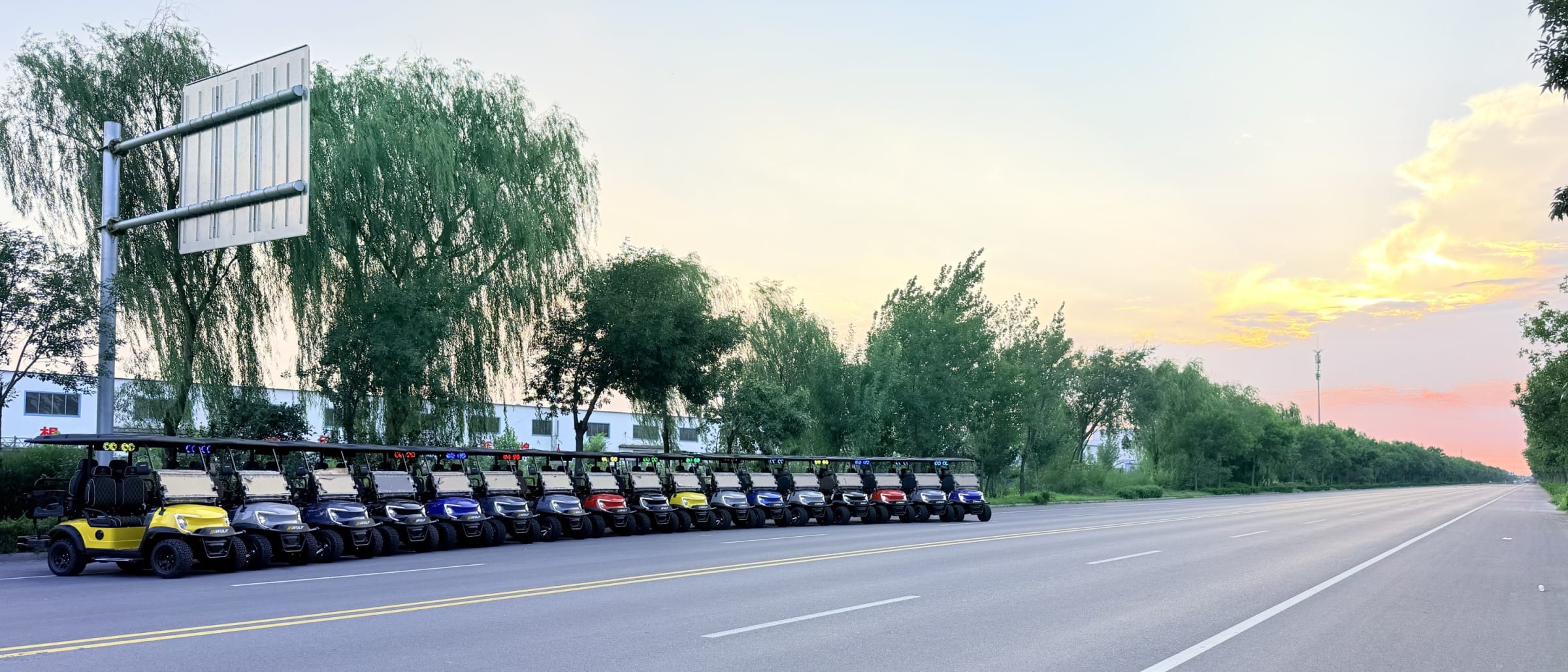 A row of Wulf golf carts beside an open road at sunset