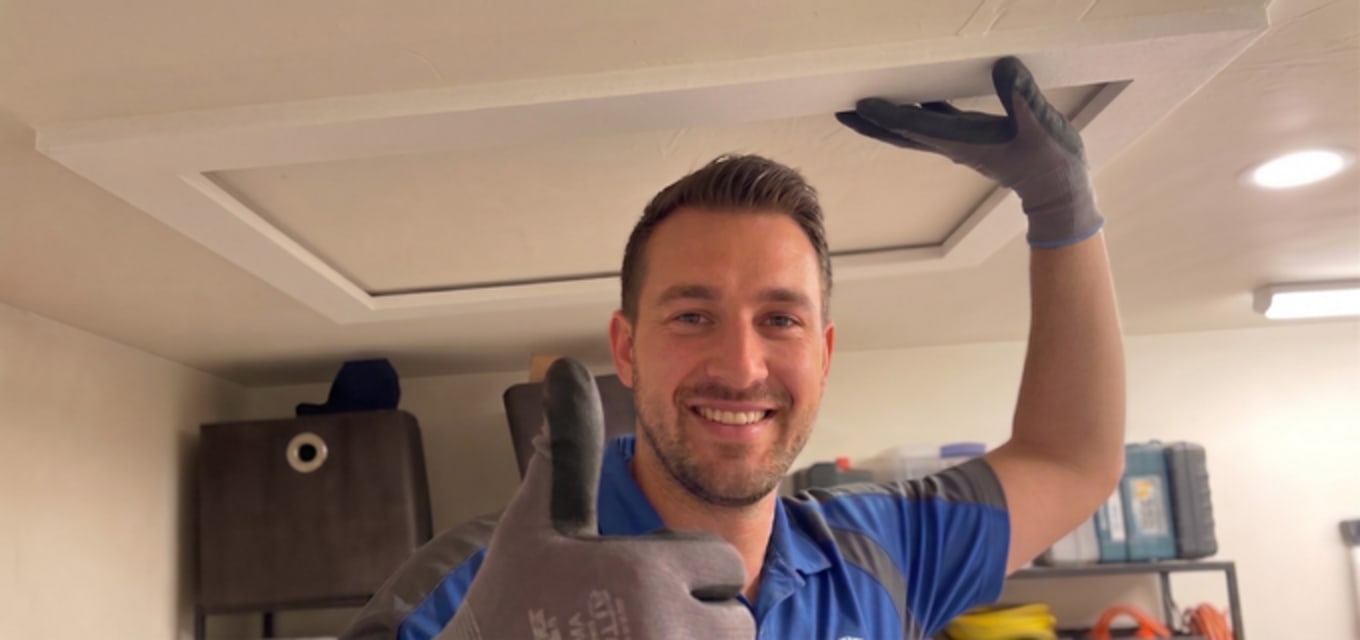HVAC tech finishing AtticFrame install on ceiling