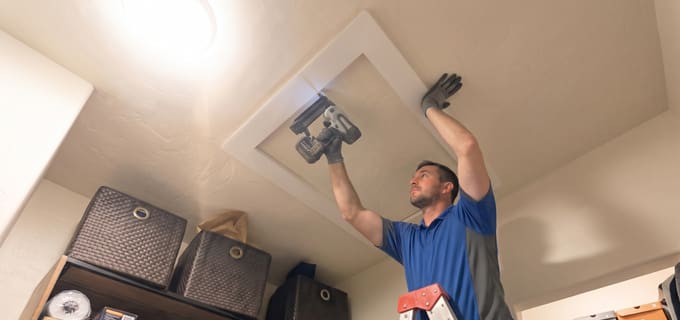 Tech nailing AtticFrame with nail gun