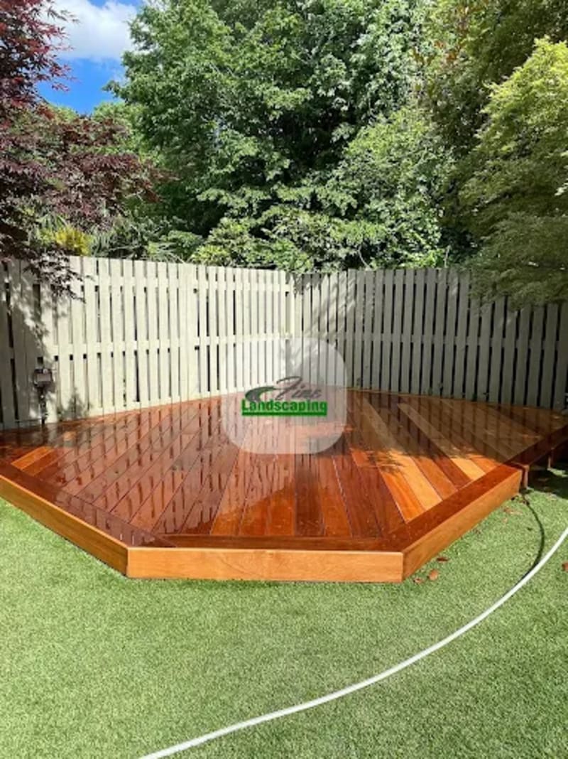 Angled timber deck against fencing at the end of a lawn