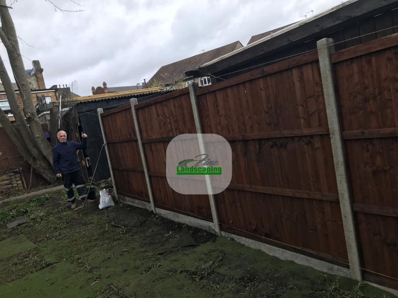 A long timber panel fence with concrete posts