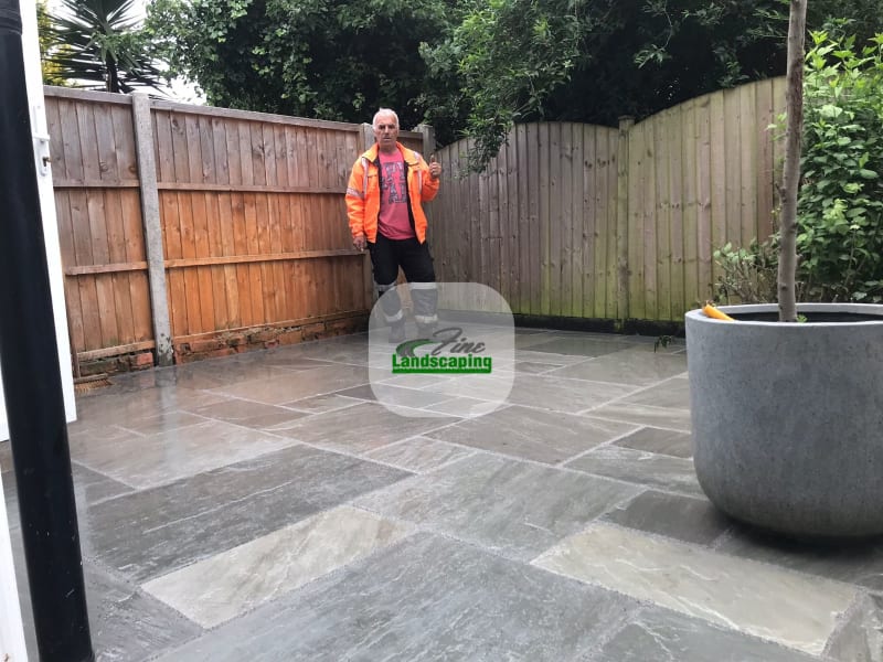 Grey patio paving beside timber fencing and a large planter