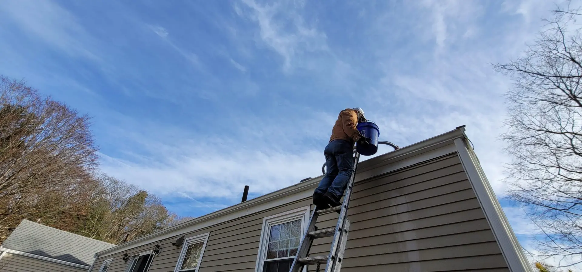 Professional technician safely cleaning gutters with proper equipment and safety gear