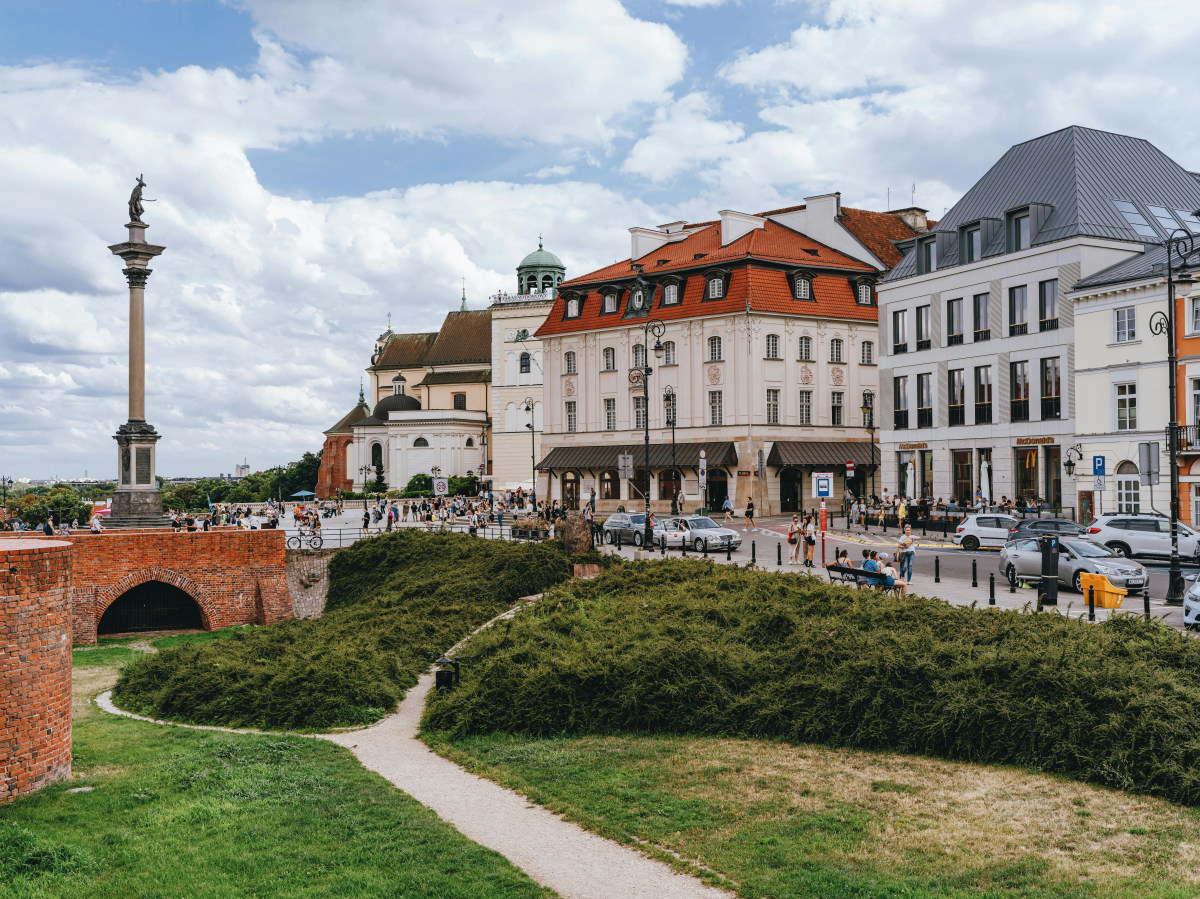 Picturesque scene of Warsaw's Old Town with historical buildings and Sigismund's Column under a bright sky.