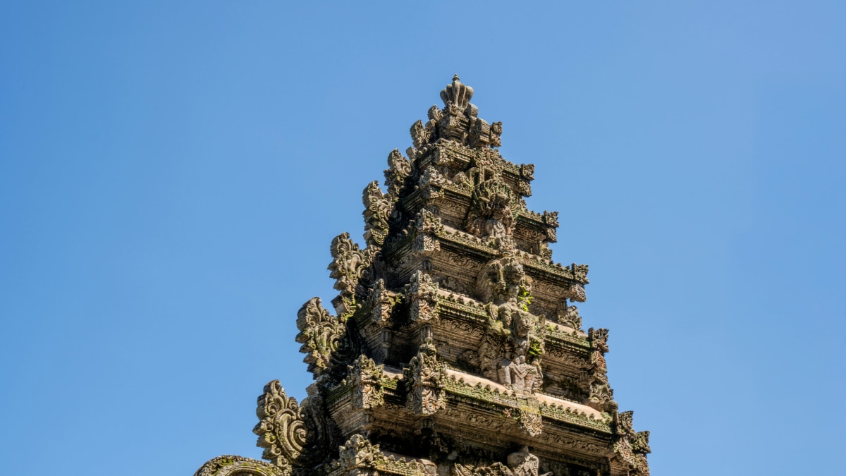 Detailed view of a traditional Balinese temple tower against a clear blue sky in Bali, Indonesia.