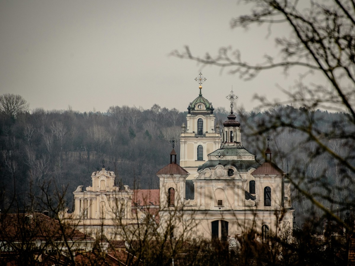 Beautiful St. John's Church towers emerging through trees in autumn, showcasing Vilnius' architectural charm.
