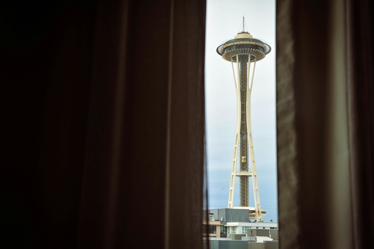 View of Seattle's Space Needle framed by curtains, showcasing iconic architecture.