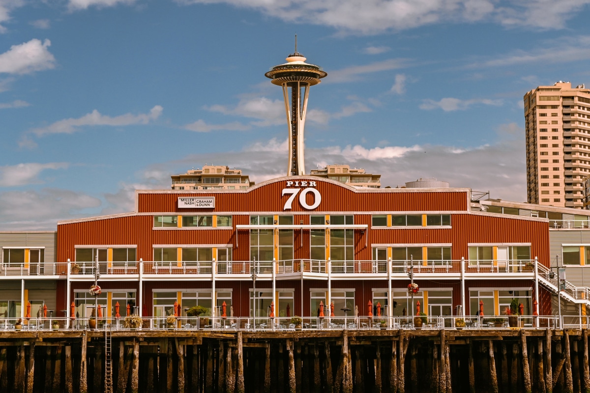 View of Seattle's iconic Space Needle behind Pier 70 against a clear blue sky.