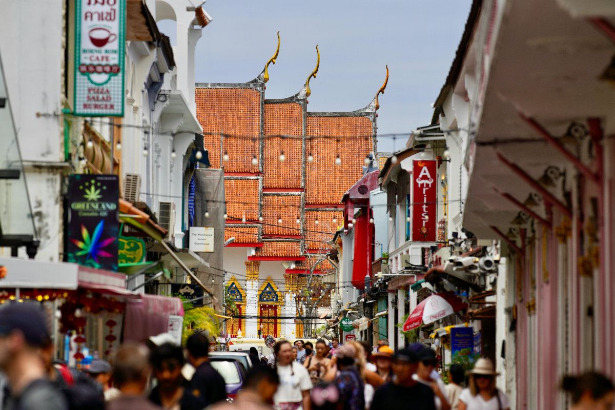 Vibrant street scene in Phuket, Thailand, showcasing traditional architecture and a busy crowd.