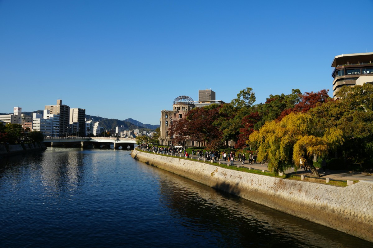 River view of Hiroshima Peace Memorial Park, vibrant autumn colors.
