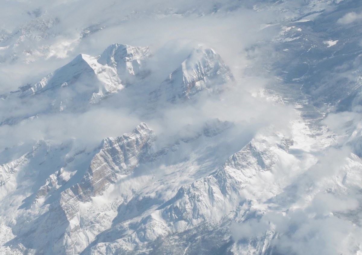 Breathtaking aerial shot of snowy peaks in the Swiss Alps during winter, enveloped in clouds.