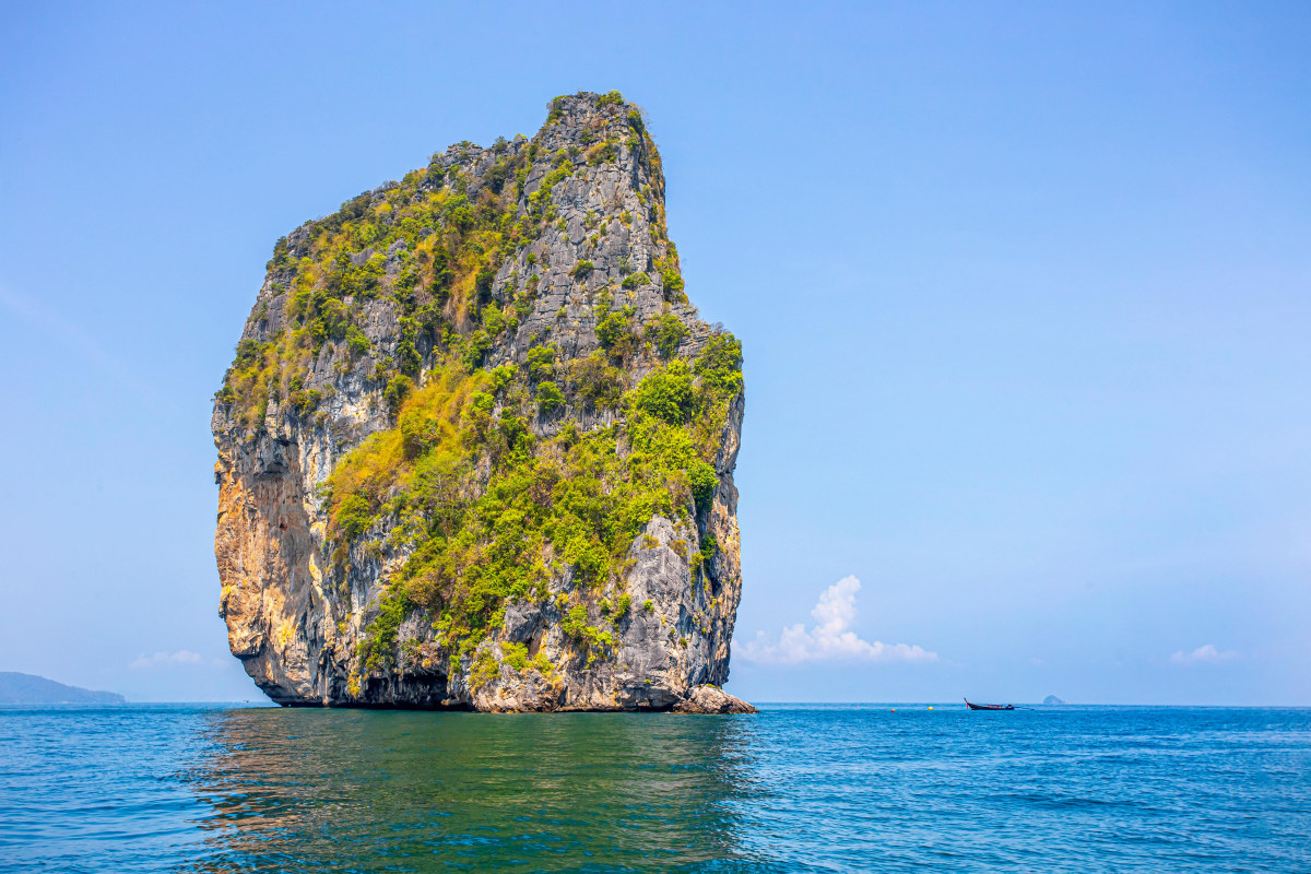 Majestic limestone island rising from the Andaman Sea under a clear blue sky in Krabi, Thailand.