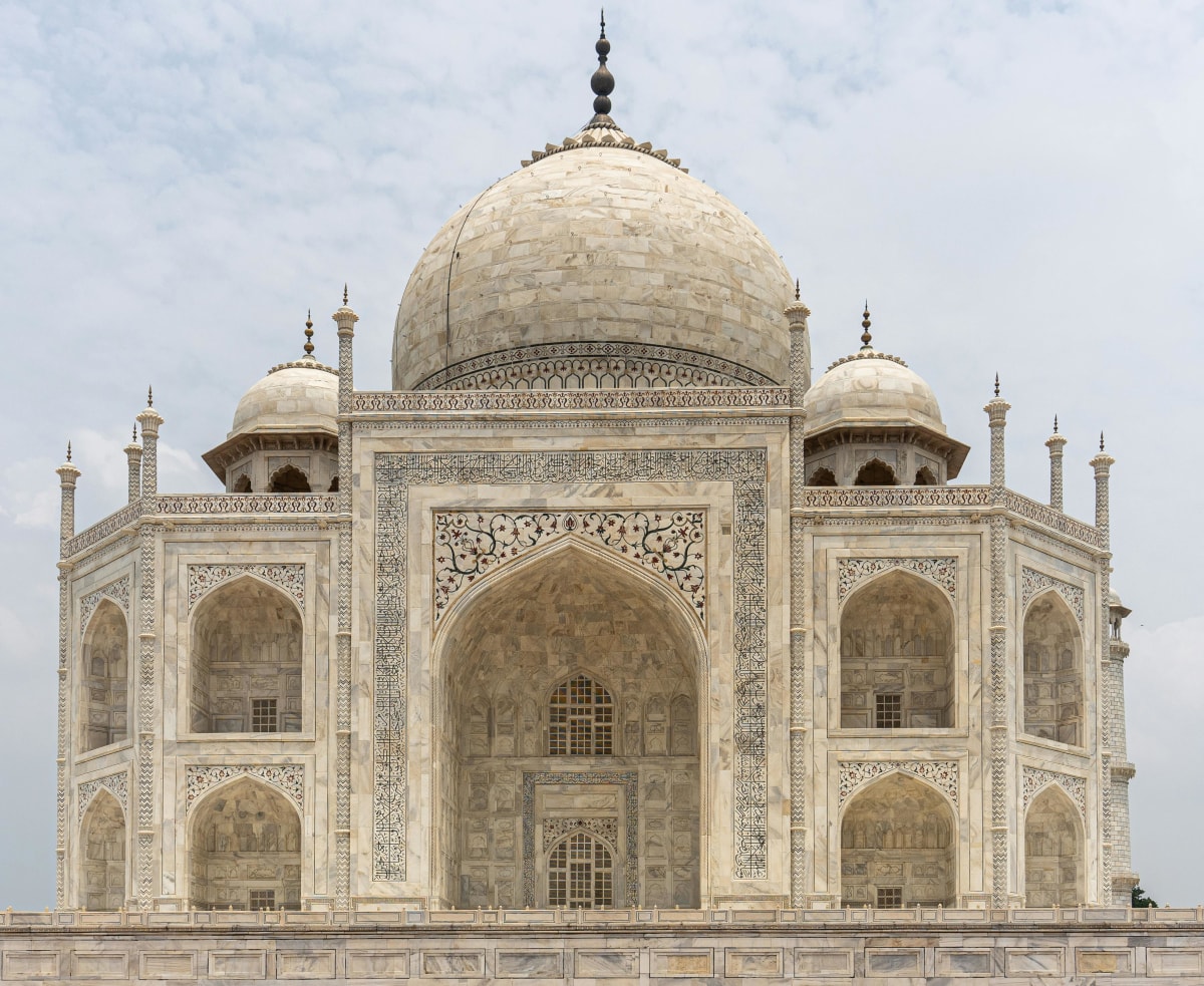 Detailed view of the Taj Mahal's iconic marble facade under a clear sky in Agra, India.