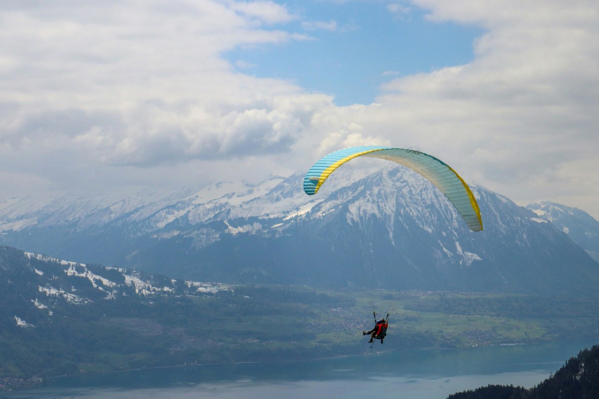 インターラーケン近くの息をのむ山岳風景を望むスイスアルプス上空のスリリングなパラグライダー。