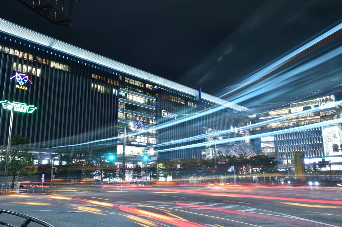 Dynamic night cityscape of Fukuoka, Japan featuring vibrant light trails and modern architecture.