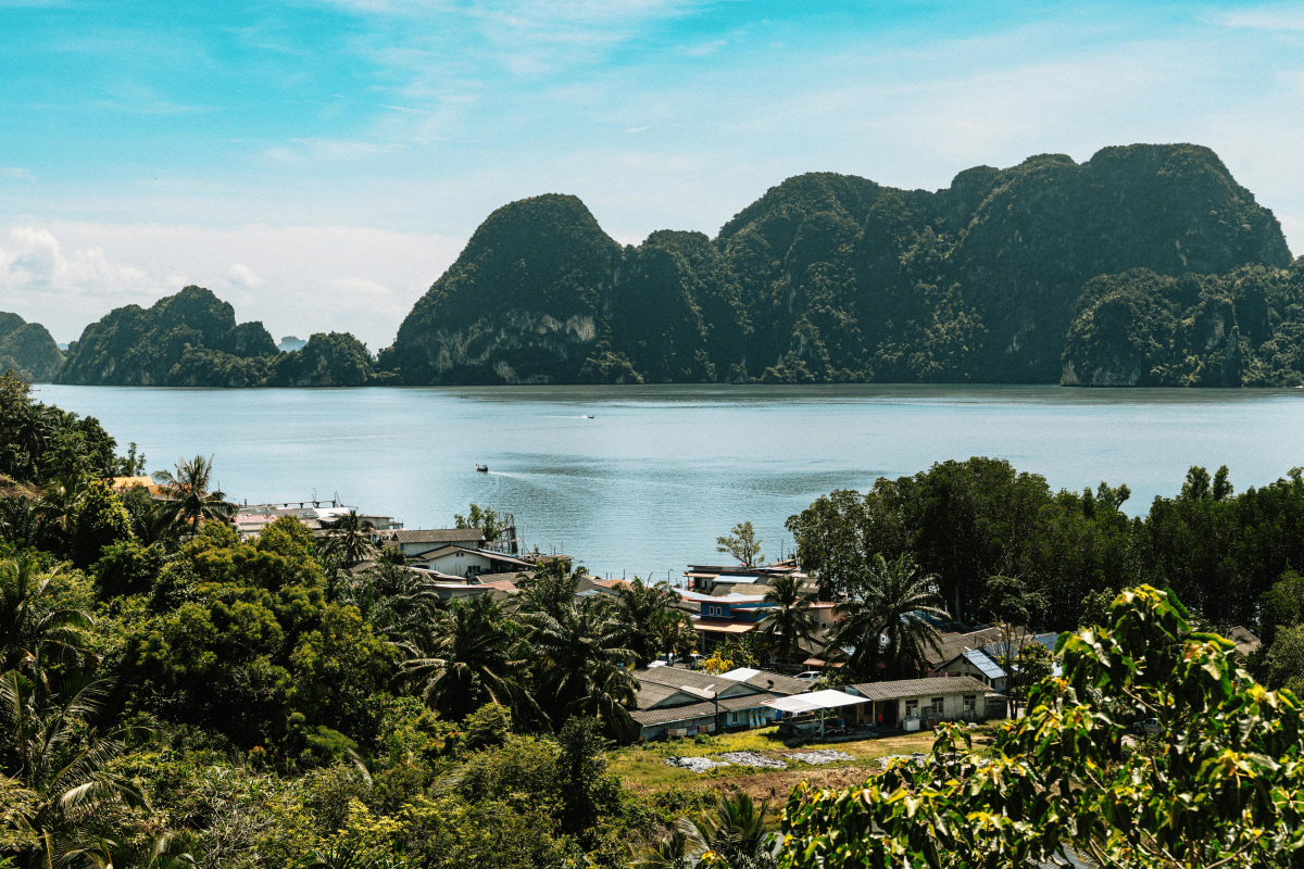 A beautiful view of Krabi, Thailand featuring lush greenery and limestone cliffs under a bright sky.