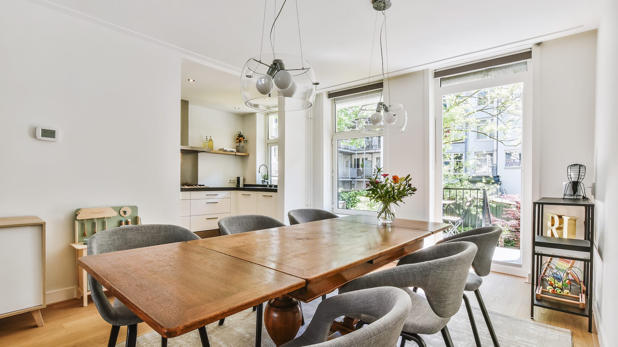 Dining room, open windows on sunny street. Vintage wooden table and chairs with rounded backs.