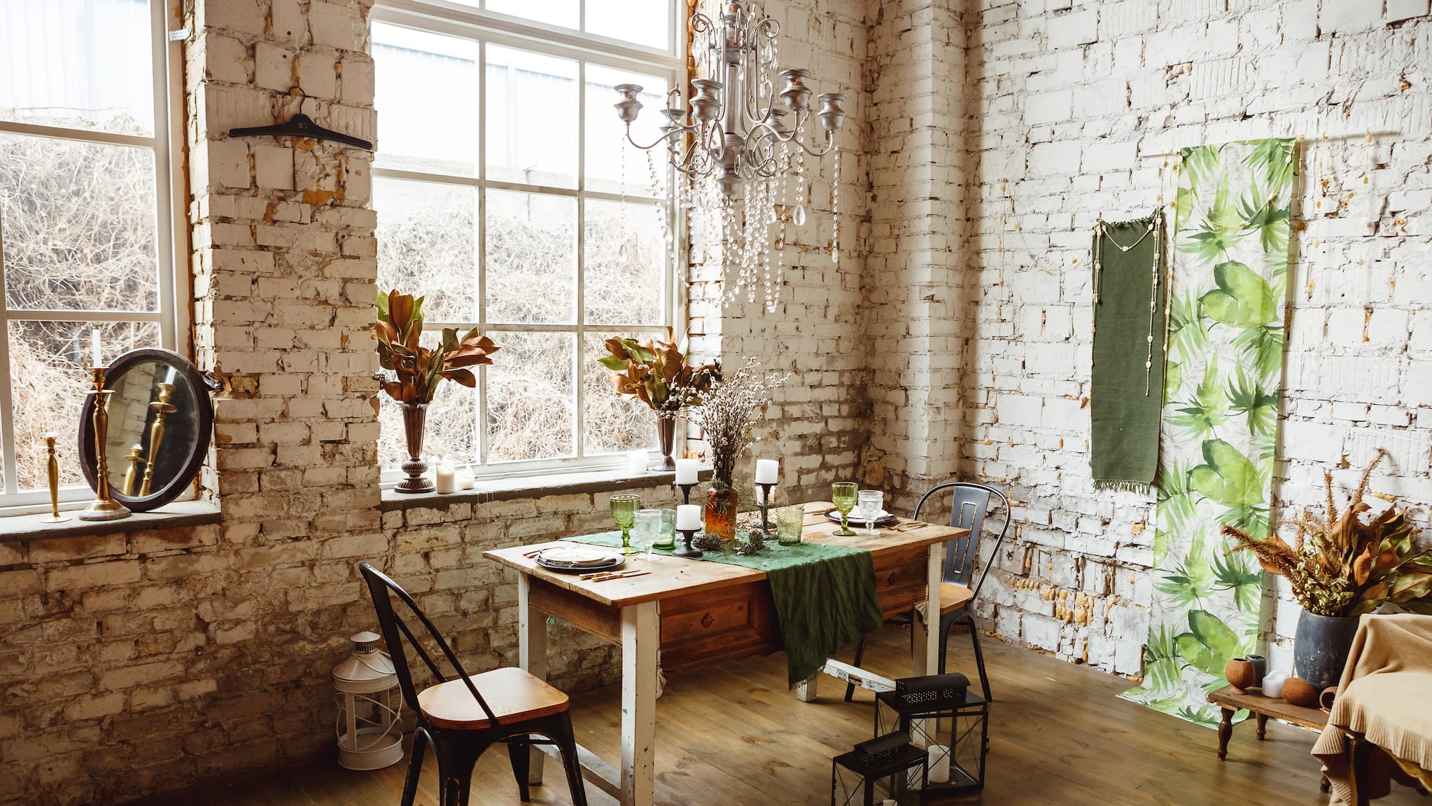 Loft with white bricks, rectangular wooden table and vintage chandelier with crystal garlands.