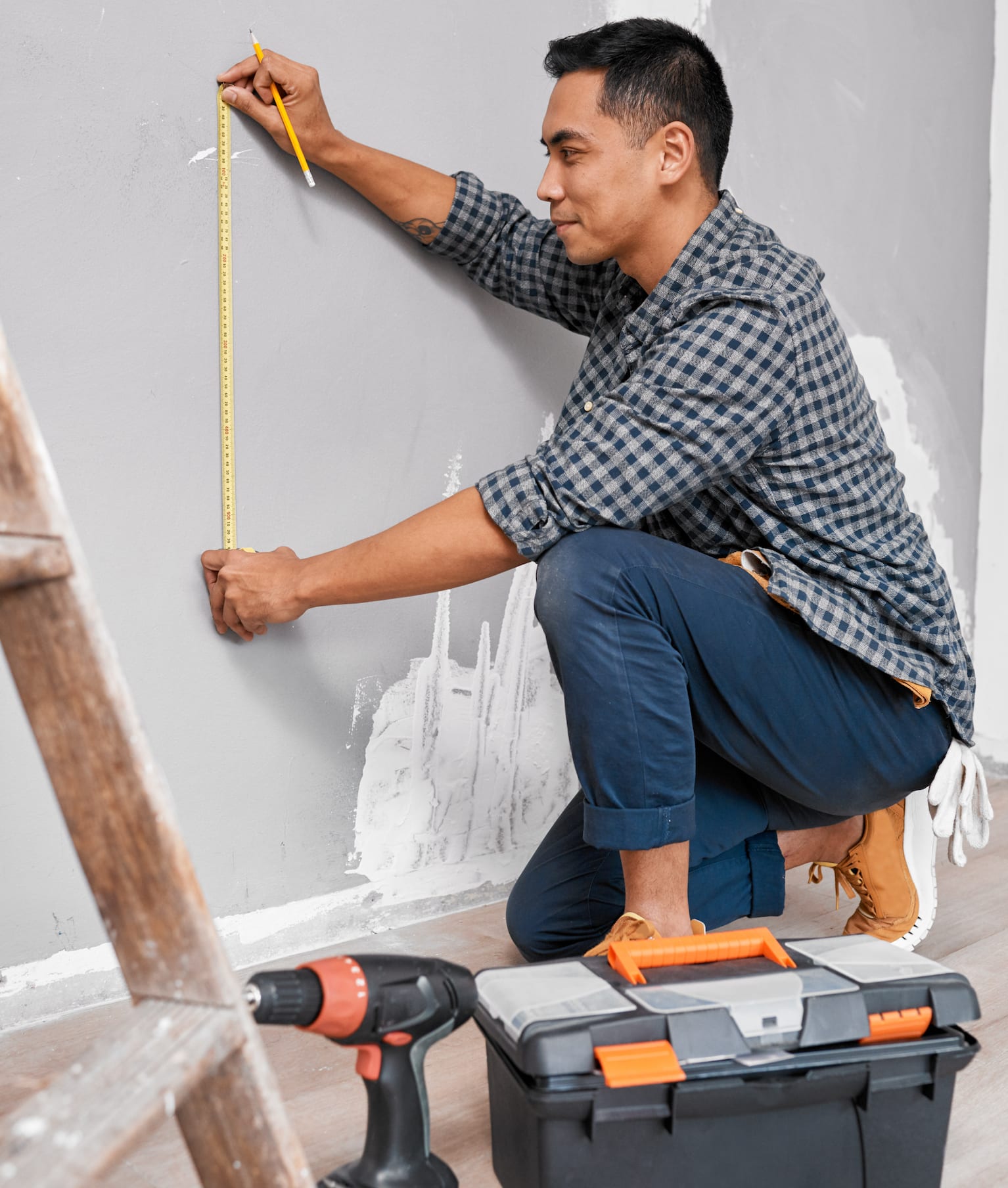 Homme utilisant un ruban à mesurer sur le mur