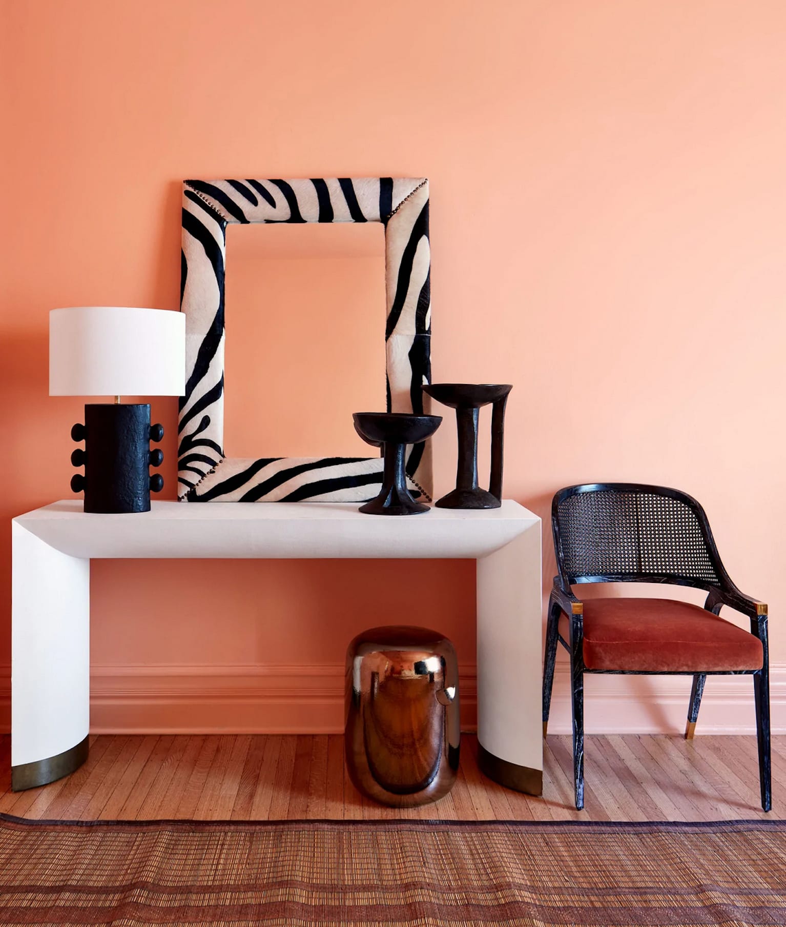 Table console accessoires noir et blanc, miroir à cadre zébré, mur orange pêche