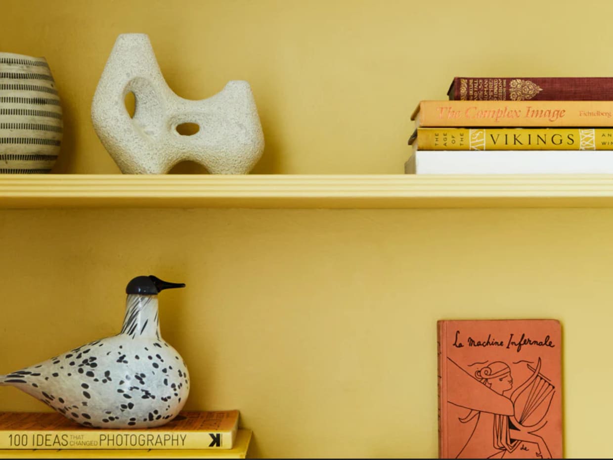 Étagères de bibliothèque jaune, livres, bibelot en forme de canard et vases