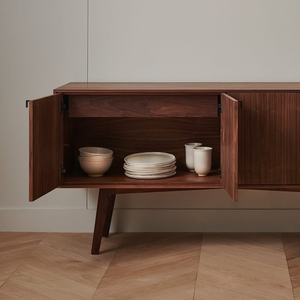 Bahut en bois foncé, porte ouverte, assiettes et bols