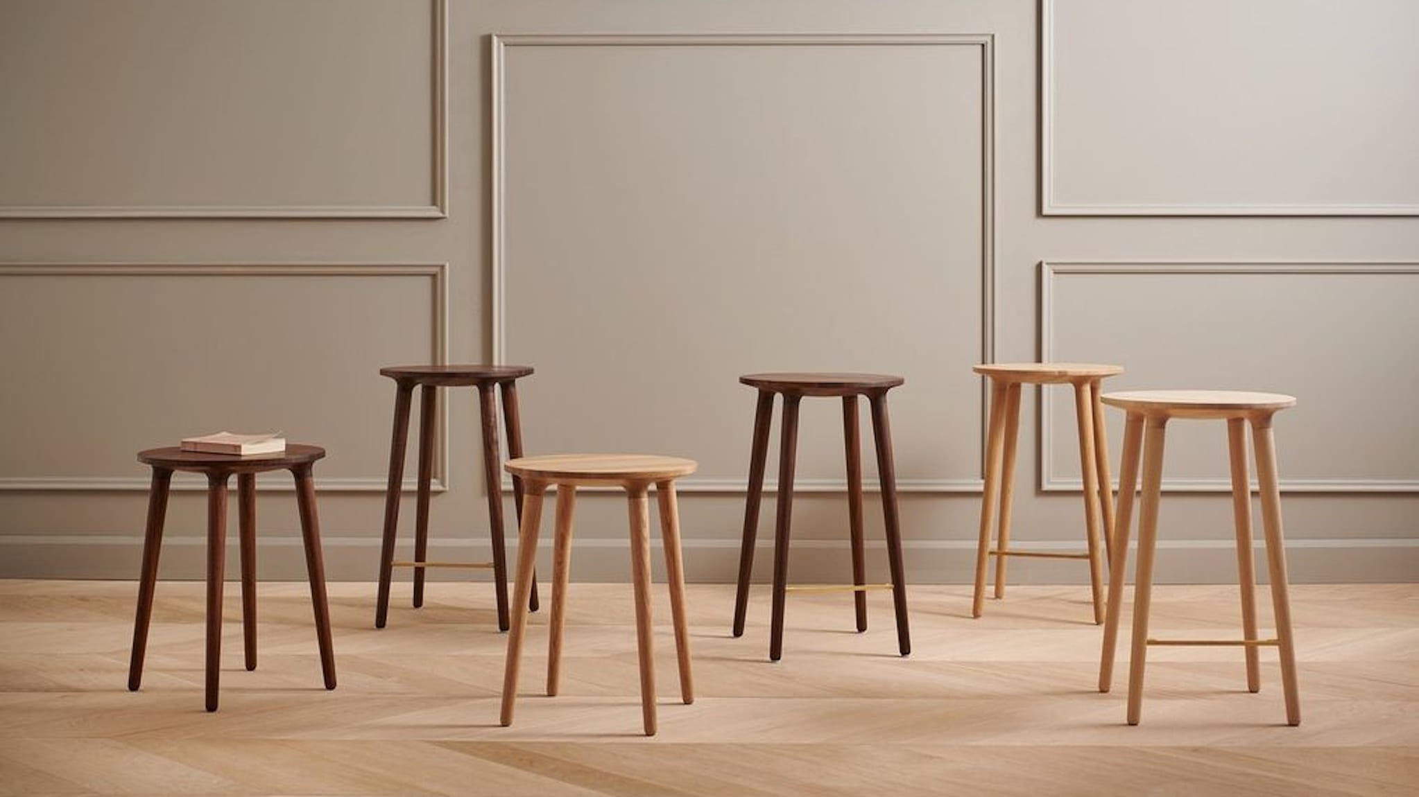 Six tabourets en bois de teintes différentes, posés sur un plancher de bois