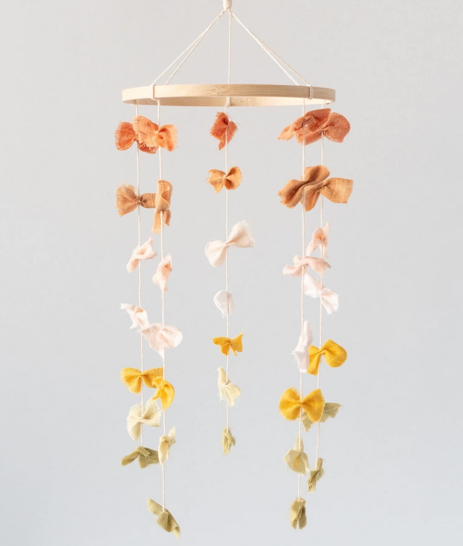 Mobile en bois et petites papillotes de coton teint enfilées sur des fils