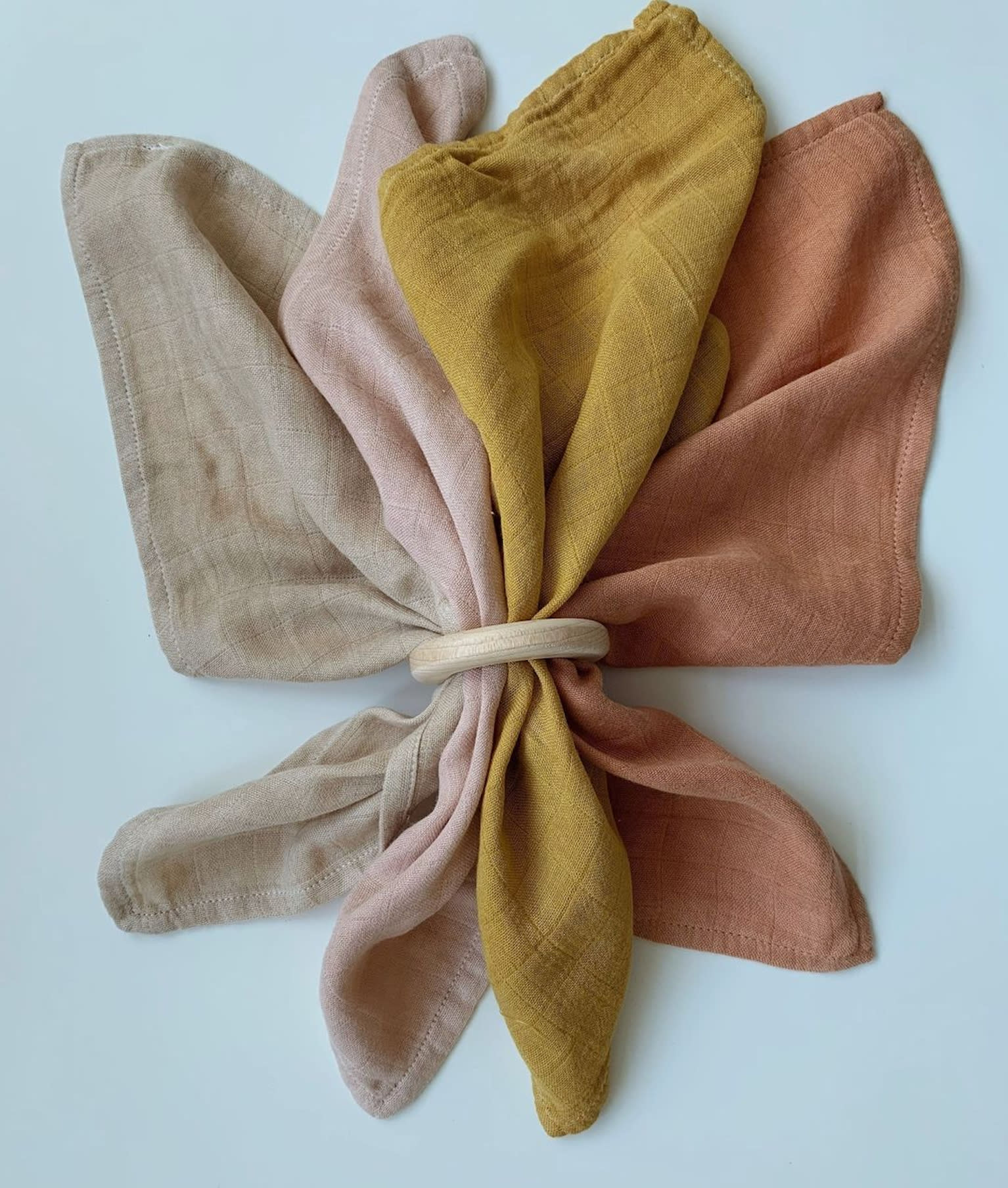 Quatre serviettes en coton teint, retenues par un anneau de bois