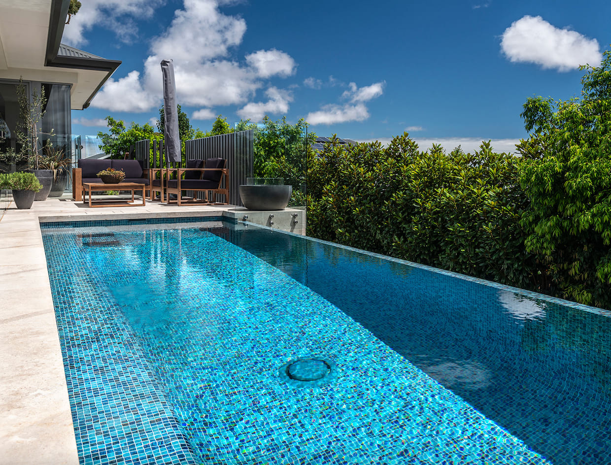 Piscine à débordement, fond mosaïque bleue, entourée d'arbres