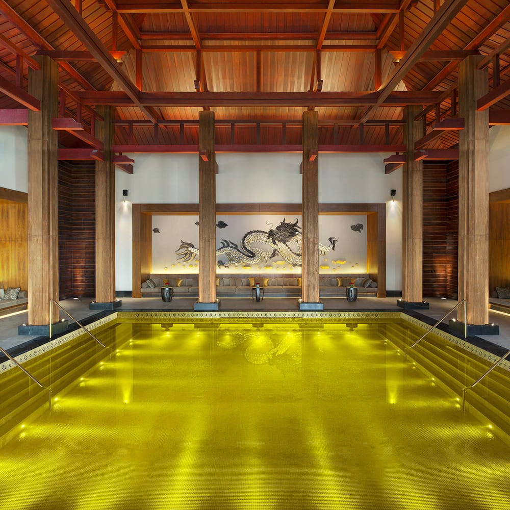 Belles piscines intérieur fond mosaïque dorée, mur avec motif de dragon, colonnes et plafond de bois