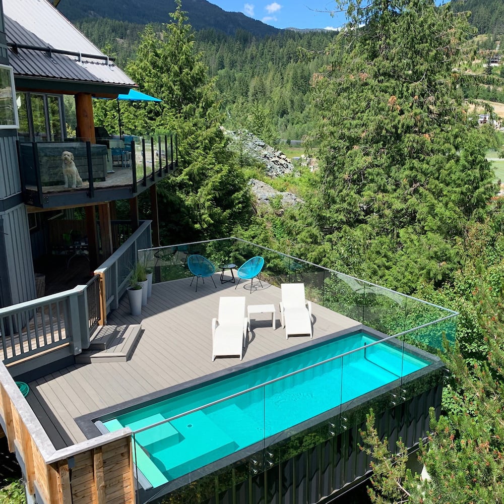 Belles piscines conteneur rectangulaire étroit, terrasse en lattes de bois, maison dans la forêt