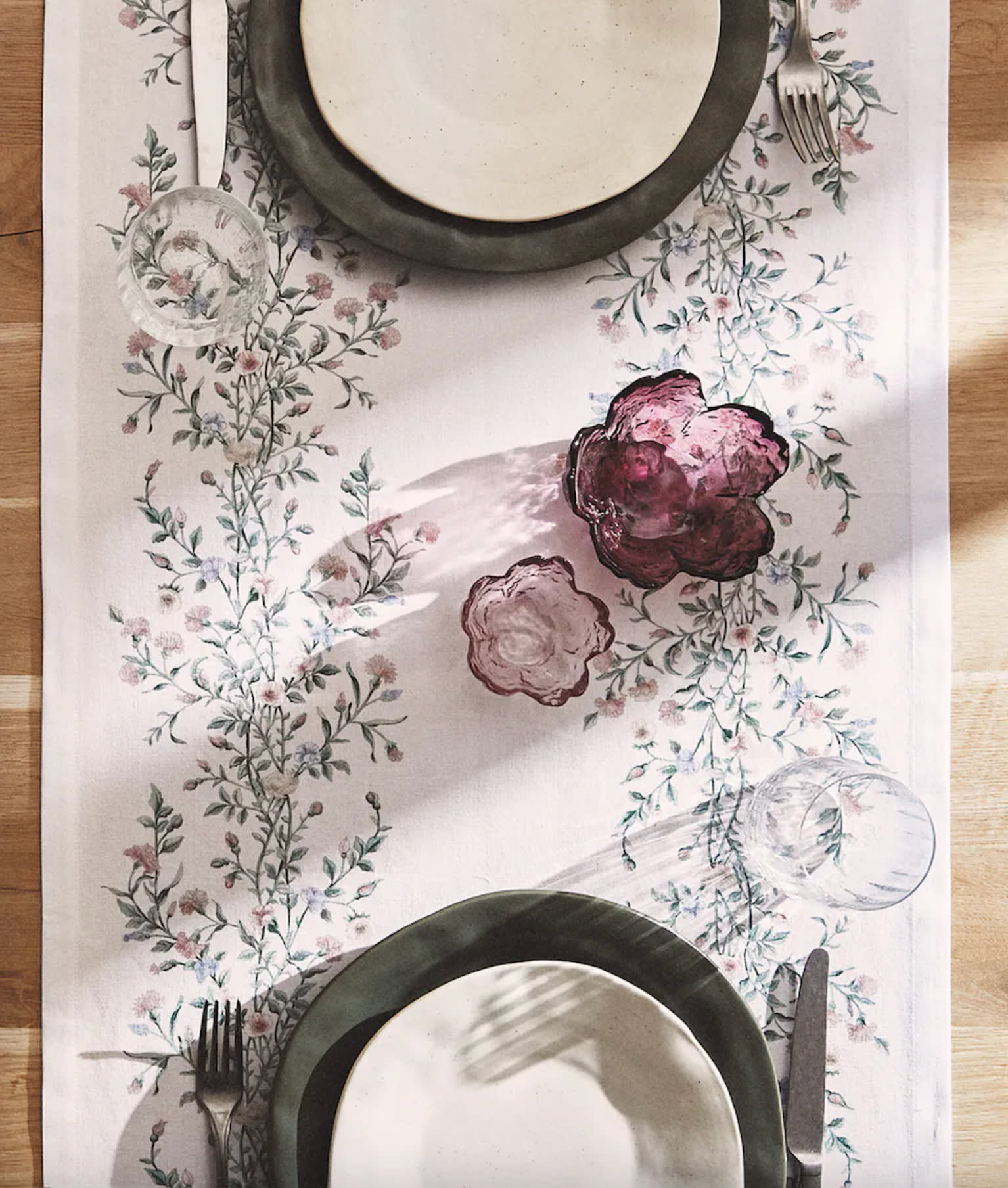 Déco voyage chemin de table à fleurs bleues et violet, deux verres violet, assiettes blanches et noires