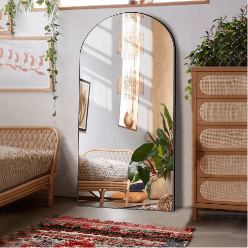 Miroir en forme d'arche posé au sol, dans un décor boho
