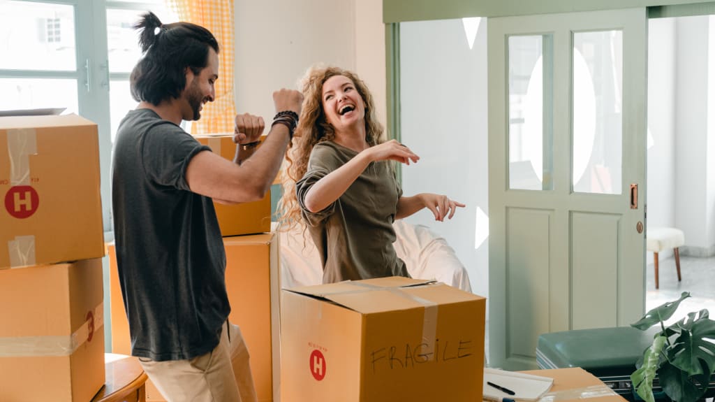 Un couple danse entre des boîtes dans leur nouvelle maison
