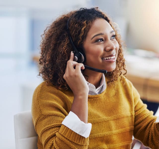 Une conseillère EspaceProprio souriante qui porte un casque d'écoute. Elle est devant un ordinateur
