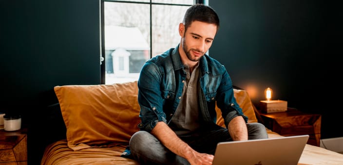 Un homme dans sa chambre qui travaille sur son ordinateur