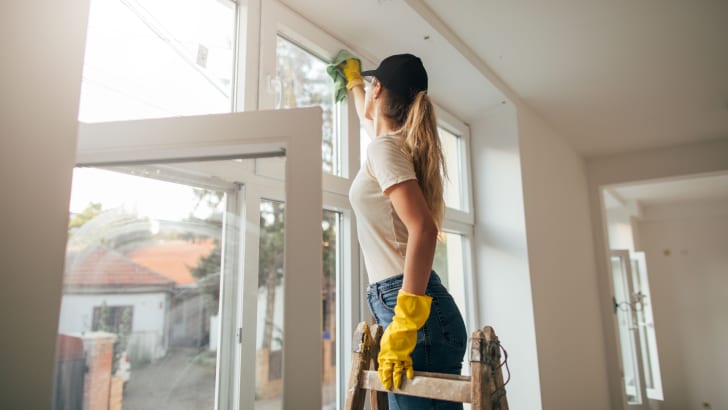 Femme lavant les fenêtres d’une maison