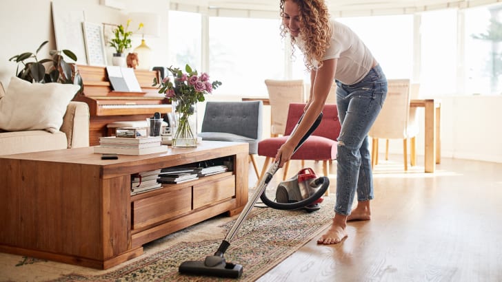 Femme passant l'aspirateur sur un tapis dans un salon