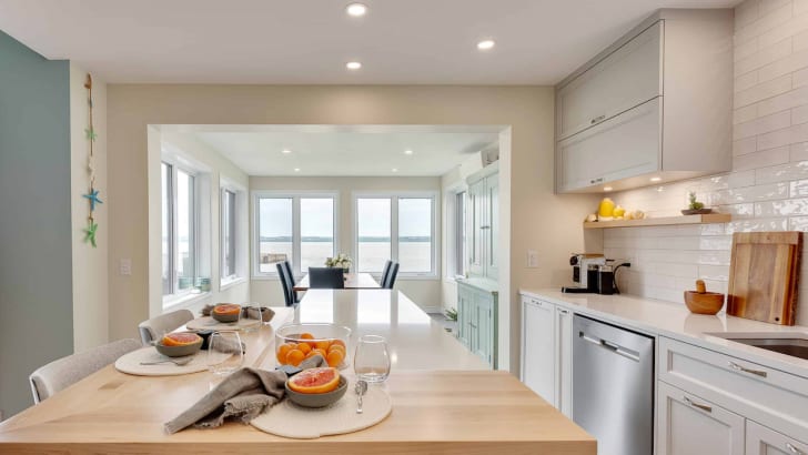 Bright white and pastel blue kitchen, large rectangular table in pale wood