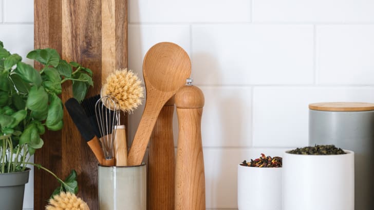 Kitchen counter with cutting board, wooden utensils, basil plant