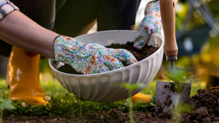 Personne ajoutant du compost dans son jardin